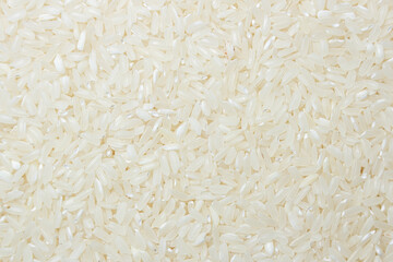 Dry Uncooked White Rice Background - Top View, Flat Lay. Scattered Raw Long Grain Rice. Asian Cuisine and Culture. Healthy Eating Ingredients. Diet Food