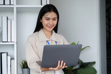 Focused Businesswoman Submitting Work on Laptop in Modern Office Environment with Professional...