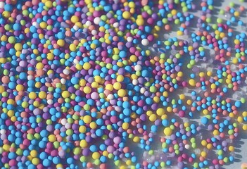 A vibrant and colorful array of small, round, multicolored beads or sprinkles spread out in a close-up view
