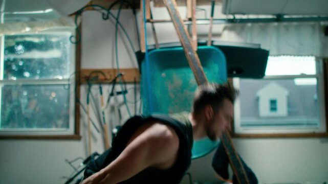 man is working out in a room with a wheelbarrow hanging on a white wall in the background