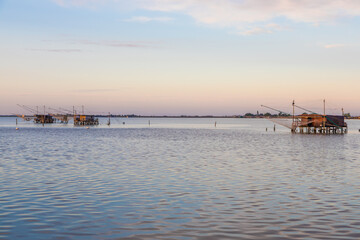 Obraz premium Italy, Comacchio lagoon. Panorama with traditional house for fishing at sunset, blue sky