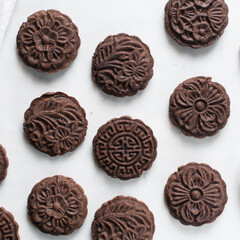 Overhead view of stamped chocolate cookies on a parchment lined baking tray, top view of embossed chocolate sugar cookies on a white background