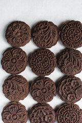 Overhead view of stamped chocolate cookies on a parchment lined baking tray, top view of embossed chocolate sugar cookies on a white background