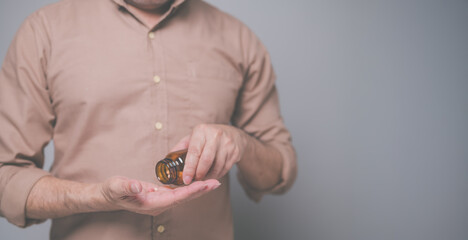 Close-up image of an individual pouring dietary supplements from brown glass bottle into palm of their hand, emphasizing health and wellness routines