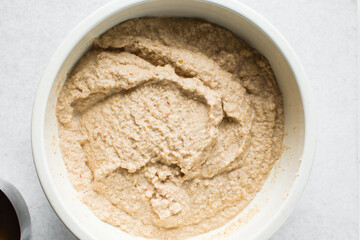 Overhead of moi moi mixture in a white ceramic bowl, top view of nigerian bean pudding being mixed, process of making nigerian moi moi