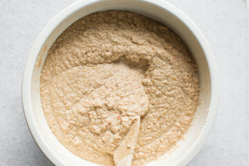 Overhead of moi moi mixture in a white ceramic bowl, top view of nigerian bean pudding being mixed, process of making nigerian moi moi