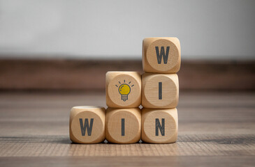 Cube, dice or blocks with message win-win with yellow  light bulb on wooden background