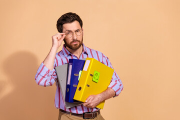 Photo portrait of attractive young man hold folders skeptical look dressed stylish striped...