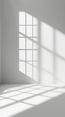 Sunlight streams through a large window, casting geometric shadows on a blank white wall and floor, creating a serene and minimalist architectural scene.