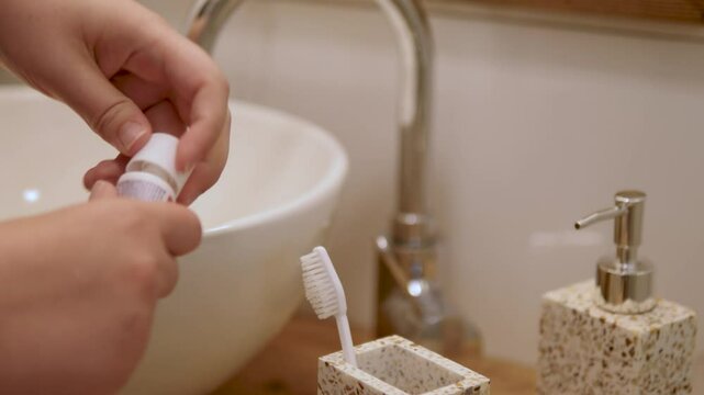 The girl takes a toothbrush and applies toothpaste that is not hers.