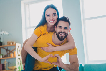 Portrait of two young people piggyback show heart symbol weekend pastime modern interior flat...