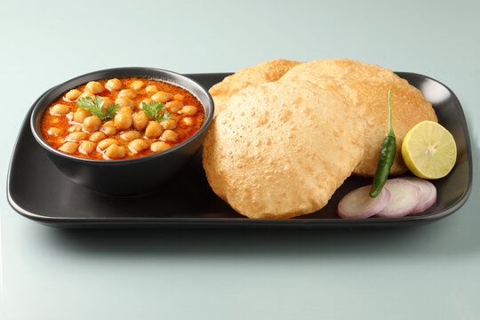 Chole Bhature or Chick pea curry with Fried Puri served in a ceramic plate and bowl