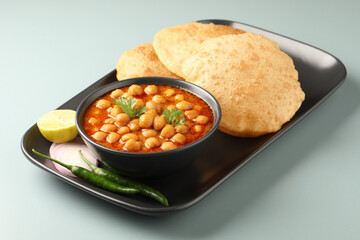 Chole Bhature or Chick pea curry with Fried Puri served in a ceramic plate and bowl