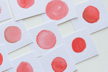 red dots on textured paper square on blank paper
