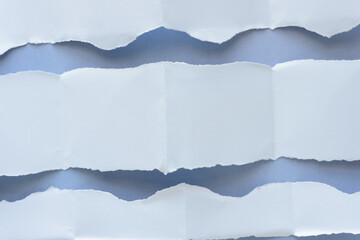 Fototapeta premium folded and torn wide paper stripes with uneven edges on blue
