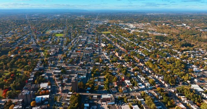 View of the modern big city with prevailing low-rise architecture. Sunny cityscape with lots of trees in the streets. Aerial view.