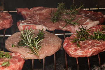 Juicy burgers and fresh steak cuts seasoned with rosemary sprigs, sizzling on a grill, perfect for a delicious barbecue or family gathering