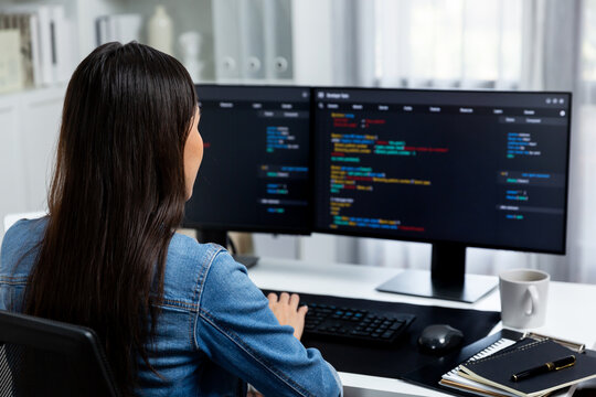 Young Asian in IT developer creating with typing online information on pc with coding program data of website application, wearing jeans shirt. surrounded by safety analysis two screens. Stratagem.