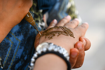 Close up photography of a woman drawing a henna tatoo on a female hand with a syringe. Casablanca, Morocco.