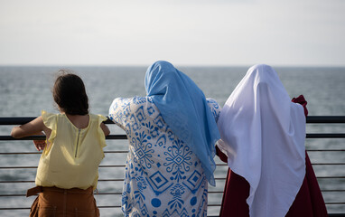 Two muslim Moroccan women and a girl looking at the Atlantic ocean. Casablanca, Morocco.