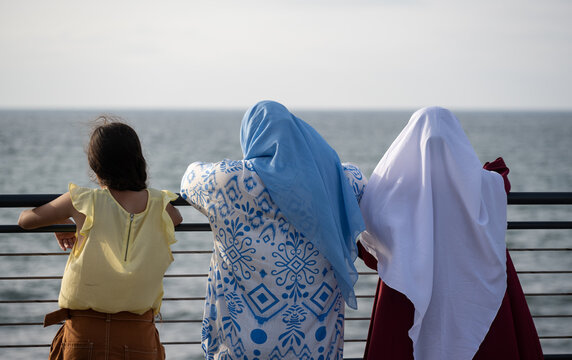 Two muslim Moroccan women and a girl looking at the Atlantic ocean. Casablanca, Morocco.