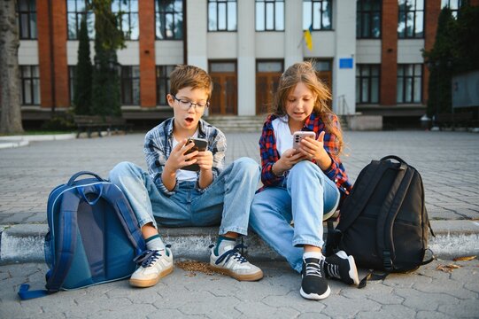 smartphone generation. schoolchildren use a smartphone on the street near the school