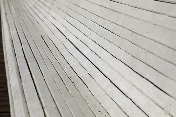 Fragment of a long bench made of wooden planks painted in white in the city of Sopot, Poland