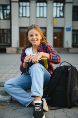 Little schoolgirl with backpack and books near school