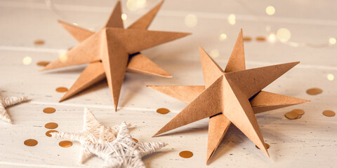 Paper Christmas stars on white wooden table. Front view.