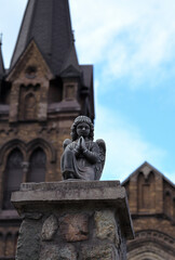 Fototapeta premium A vertical photo of a close-up angel sculpture on the stone fence of St. Nicholas Church against the backdrop of the blue sky in the city of Kamianske, Ukraine