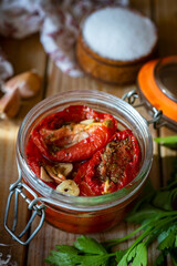 Dried tomatoes with spices and garlic in a glass jar on a wooden table. Dried tomatoes in a jar. Vertical photo.Close-up
