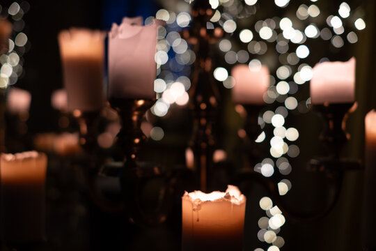 Soft candlelight illuminates a romantic setting with blurred fairy lights in the background during an evening gathering - Powered by Adobe