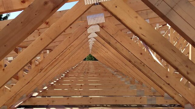 Close-up of wooden roof trusses forming a geometric pattern during the construction of a building under clear daylight