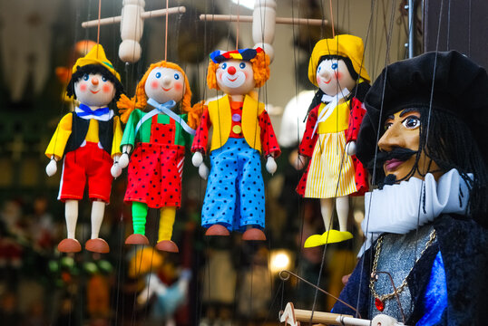 A photograph of many homemade dolls in colorful clothes at a puppet theater on a city street.