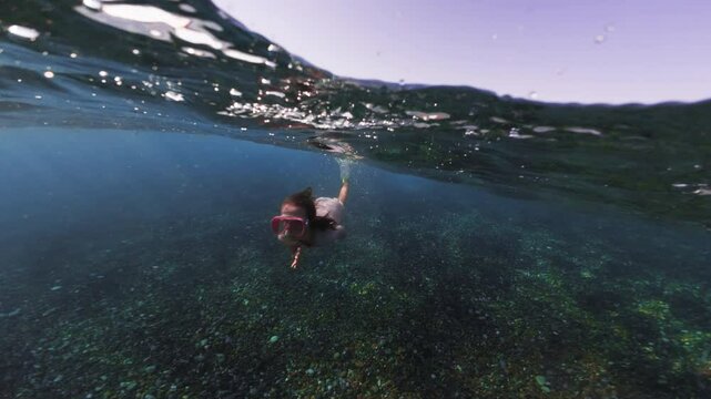 A child dives and swims under water in a mask. Snorkeling and active recreation of a girl with a family snorkeling in the ocean. High quality 4k footage