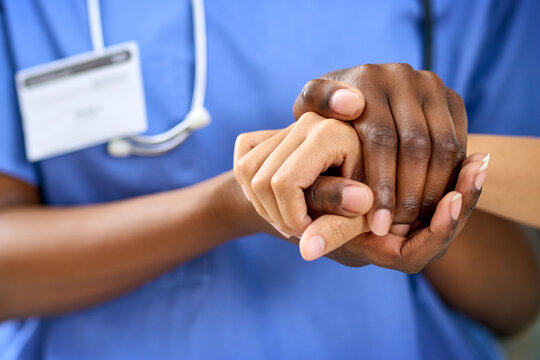 Doctor, nurse and holding hands with patient for empathy, sympathy or care in support at hospital. Closeup, medical employee or caregiver with touch for understanding, healthcare or help at clinic