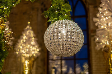 Obraz premium Elegant crystal chandelier hanging in a beautifully decorated hall during festive celebrations at night.Background with Luxurious Christmas decorations and crystal chandeliers and lights