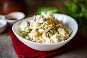 Breakfast for the whole family: salad with peas, chicken, cucumbers, chicken eggs and mayonnaise. Festive salad in a white plate. Close-up.