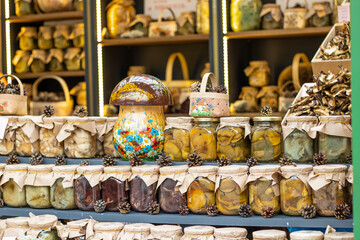 A bright, original shelf with jars of various salted mushrooms.