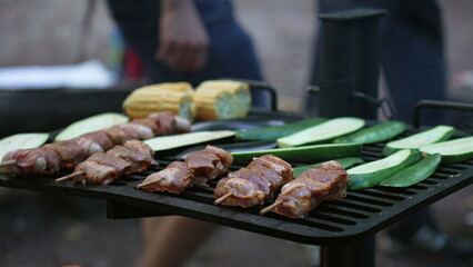 Skewers and vegetables grilling over a flame, showing a delicious assortment of food being cooked outdoors, capturing the essence of outdoor cooking and barbecue