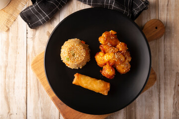 Sweet and sour chicken with fried rice and crispy spring roll, American Chinese food made out of fried, battered chicken covered with sauce. Tasty dish popular in many countries.