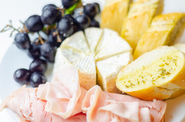 A plate of food with bread, cheese, and grapes