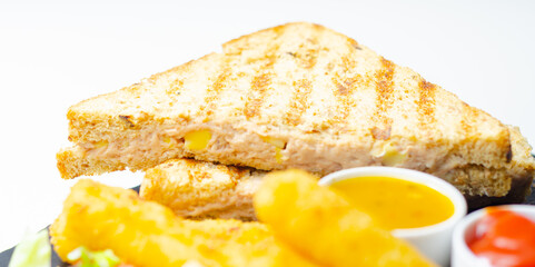 A plate of food with a sandwich, cheese sticks, and ketchup