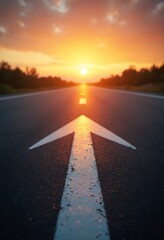 Low angle photography captures a white arrow on an asphalt road during sunset, showcasing the straight ahead concept, path to success