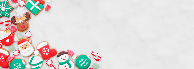 Cute colorful Christmas cookie corner border on a white marble banner background with copy space. Overhead view. Holiday baking concept.