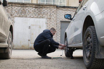 The driver independently spins the wheel on the car, raised on a jack, near the garage