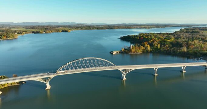 Aerial view of Lake Champlain Bridge during autumn, spanning the serene lake and connecting Crown Point, New York to Vermont, with fall foliage and distant mountain ranges under clear skies.