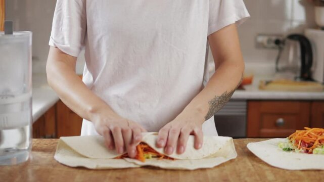 Chef skillfully wrapping tortilla around savory blend of meat and fresh vegetables creates mouthwatering burrito in lively kitchen filled with vibrant colors and fresh ingredients