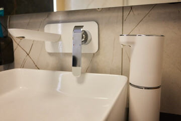 Fototapeta premium A modern bathroom sink with a sleek faucet and soap dispenser, enhancing the spaces aesthetic