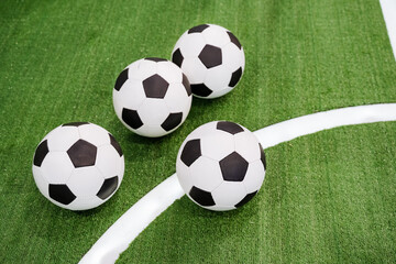 Three brightly colored soccer balls are resting peacefully on a vast, lush green field under the...